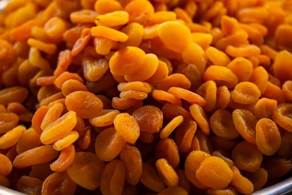 A bowl filled with plump, dried orange raisins, showcasing their rich color and texture.
