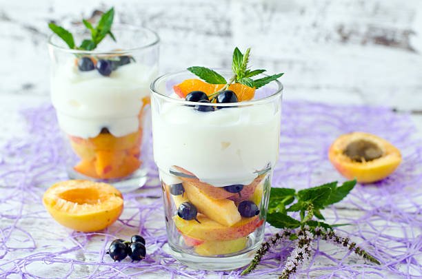 A glass filled with a layered apricot dry fruit yogurt parfait, showcasing vibrant colors and textures of the dessert.