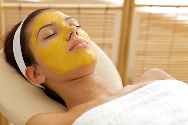 A woman wearing a apricot dry fruit face mask, highlighting her facial features and expression in a vibrant setting.