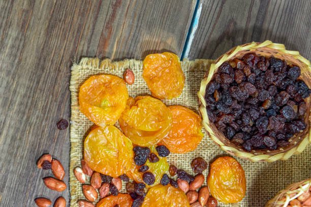  A wooden table displaying an assortment of dried fruits, including apricot dry fruit, and various nuts arranged attractively.