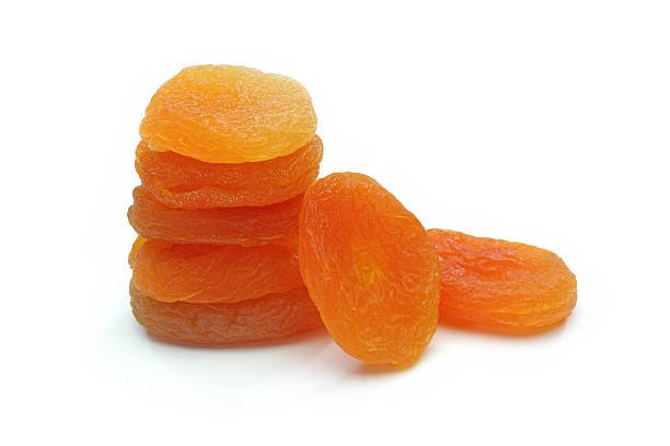 A collection of dried apricots arranged on a clean white background, showcasing their rich orange color and texture.