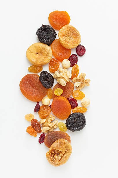 A variety of dried fruits and nuts arranged on a white background, showcasing their natural colors and textures.