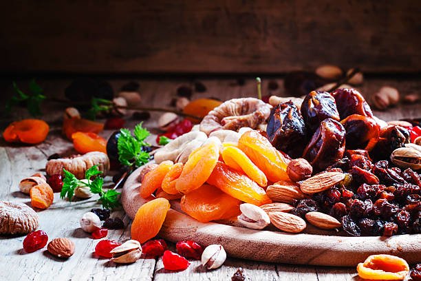 A wooden table adorned with a variety of nuts and dried fruits, including apricot dry fruit, creating a rustic display.