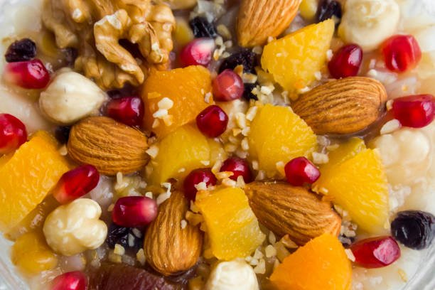 A bowl of oatmeal topped with assorted nuts and fresh fruit, showcasing a nutritious and colorful breakfast option.