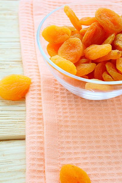 A bowl filled with plump, dried apricots, showcasing their rich orange color and natural texture.