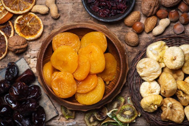 A variety of dried fruits and nuts arranged on a rustic wooden table, showcasing their natural colors and textures.