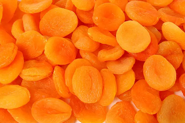 A collection of dried apricots arranged on a white background, showcasing their rich color and texture.